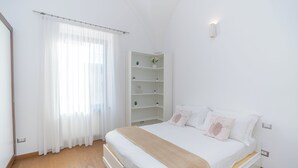 A bedroom with a bed, a white wardrobe, a shelf unit, and a window with sheer curtains. - La Casa di Sasà - Maiori - Amalfi Coast - Elegant Accomodation (Maiori)