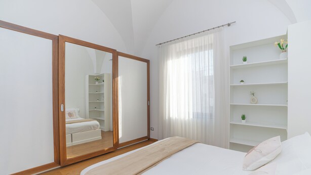 A bedroom with a bed, a wardrobe, and a shelving unit with plants. - La Casa di Sasà - Maiori - Amalfi Coast - Elegant Accomodation (Maiori)