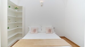 A bedroom with a bed, two pillows, a bedside table, a nightstand, a white wardrobe, and a small wall-mounted light. - La Casa di Sasà - Maiori - Amalfi Coast - Elegant Accomodation (Maiori)