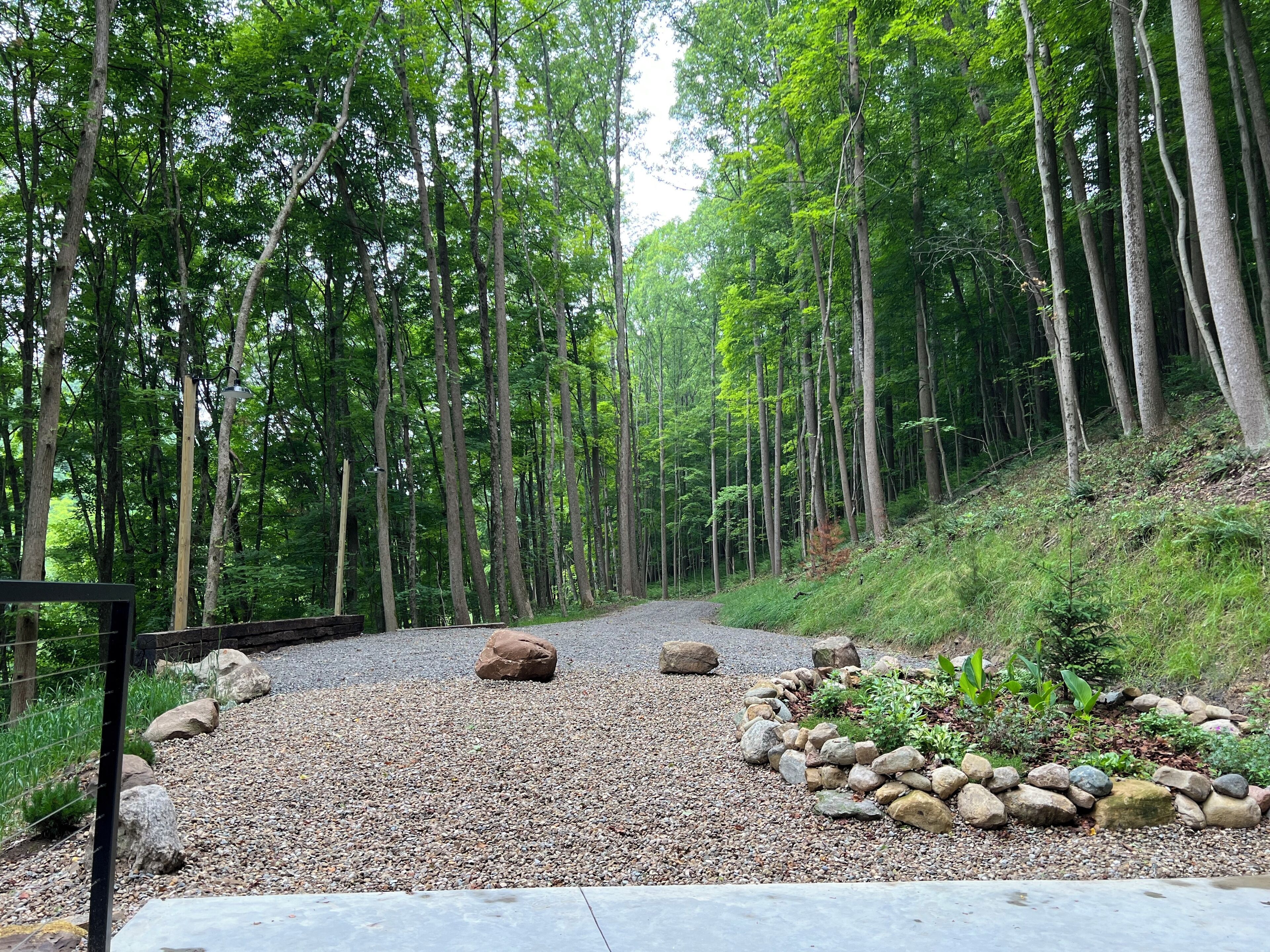 Un sentier de gravier bordé d’un jardin de rochers et d’une forêt dense.