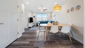 A modern kitchen with a dining area, white cabinets, and a ceiling fan. - Newly Built Luxury Townhouse in Ortley Beach! (Seaside Heights)