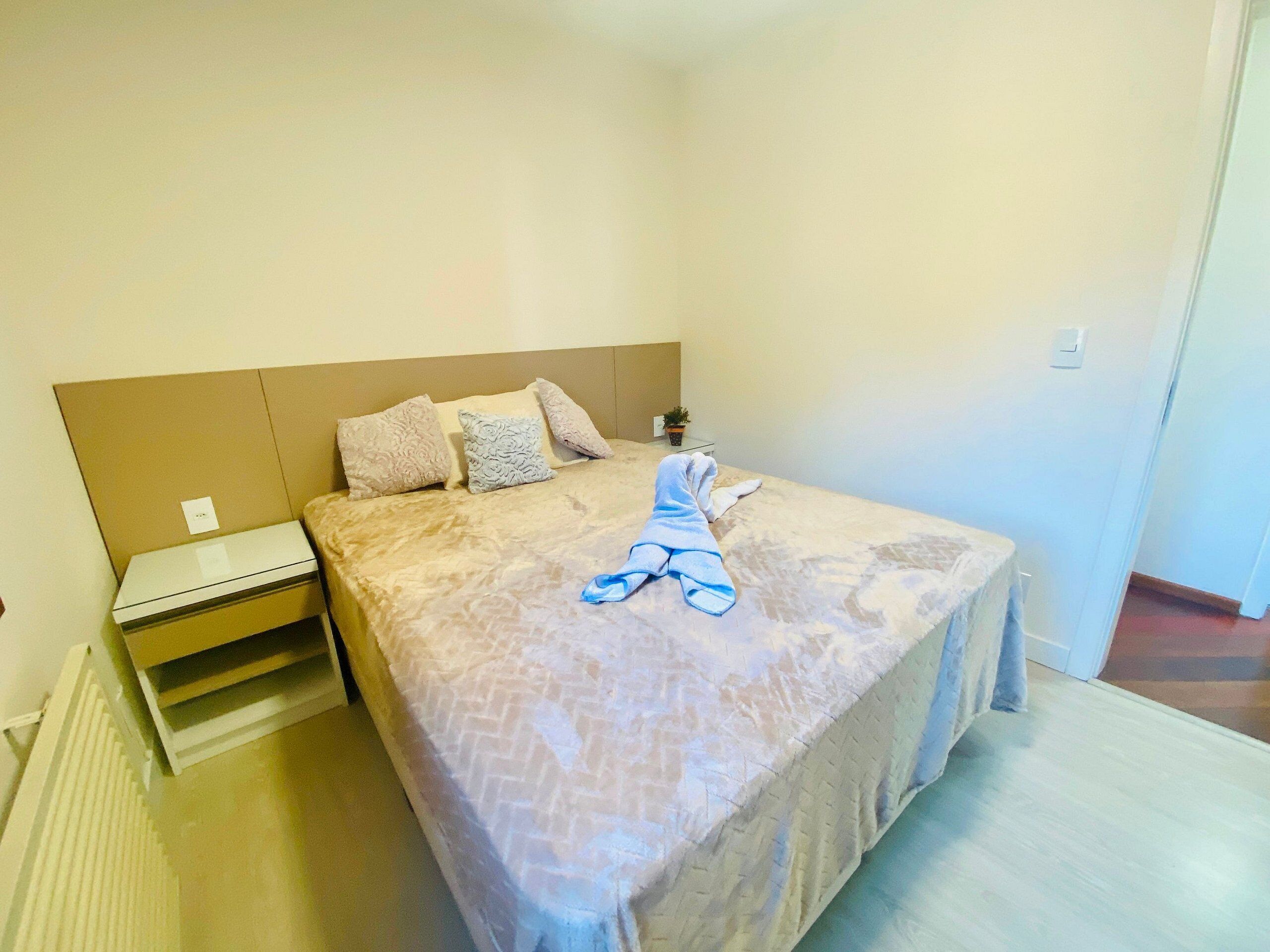 Ein Schlafzimmer mit einem Bett, einem Nachttisch, einer Topfpflanze und einer Heizung.