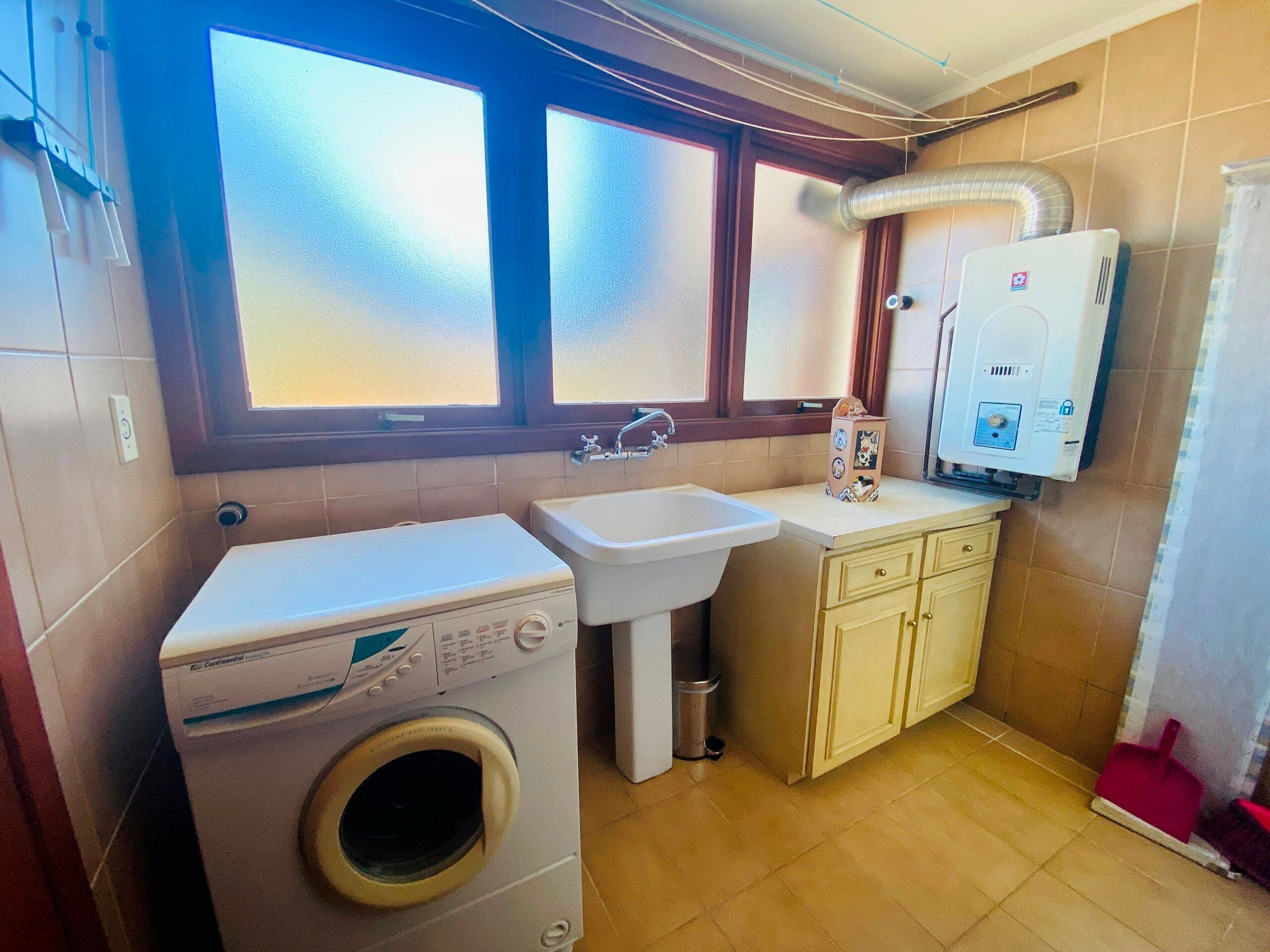 A compact kitchen with a washing machine, sink, and a water heater.