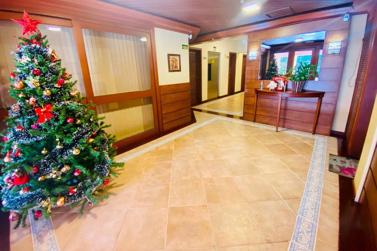 A hotel lobby with a Christmas tree, wooden paneling, and a reception desk.