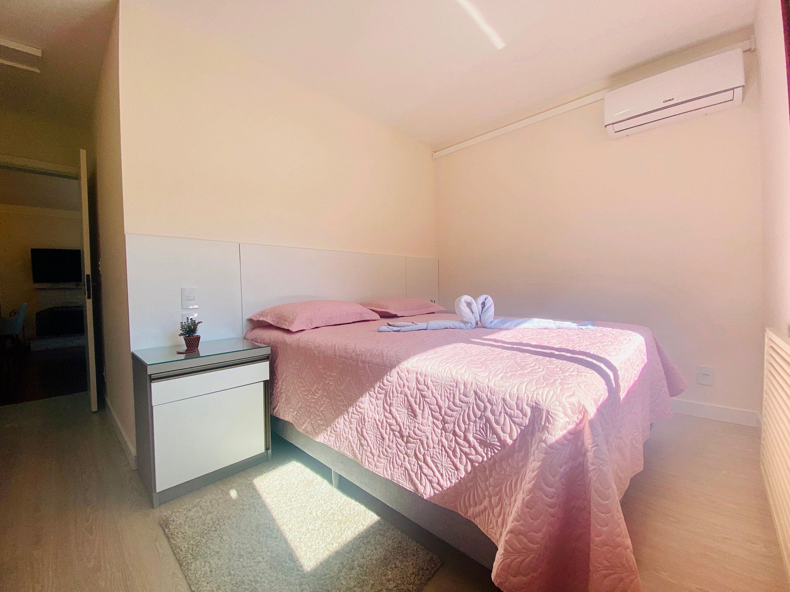 Un dormitorio con cama, mesita de noche y unidad de aire acondicionado.