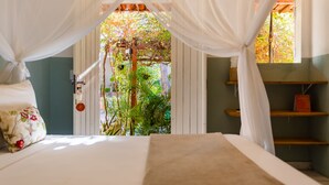 Ein Schlafzimmer mit Baldachinbett, kleinem Fenster und Blick auf einen Garten.