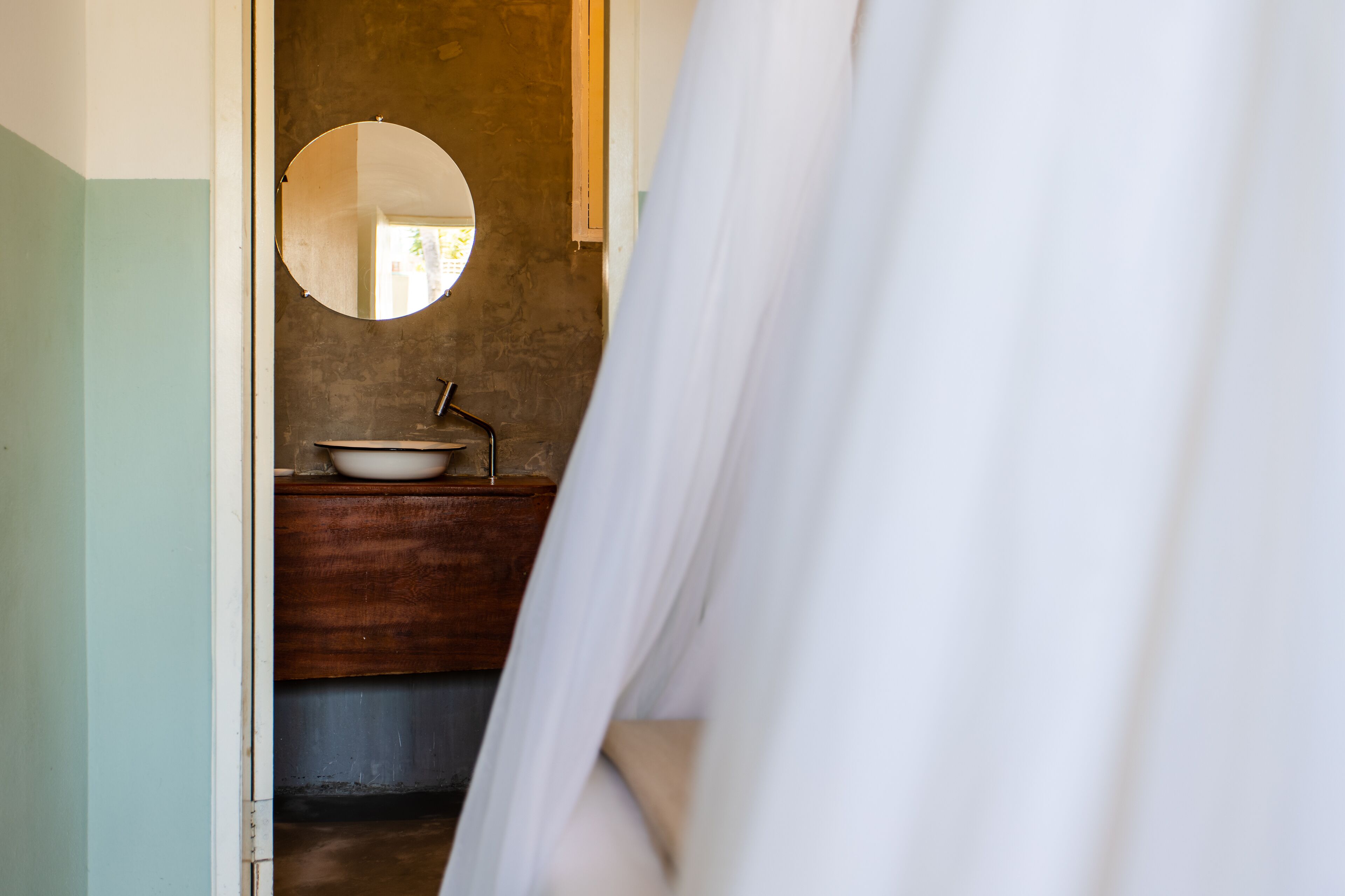 A bathroom with a wooden vanity, a round mirror, and a white sink.