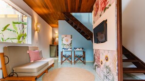 Ein gemütlicher Wohnbereich mit einer Couch, Sesseln, einem Teppich und einer Treppe.