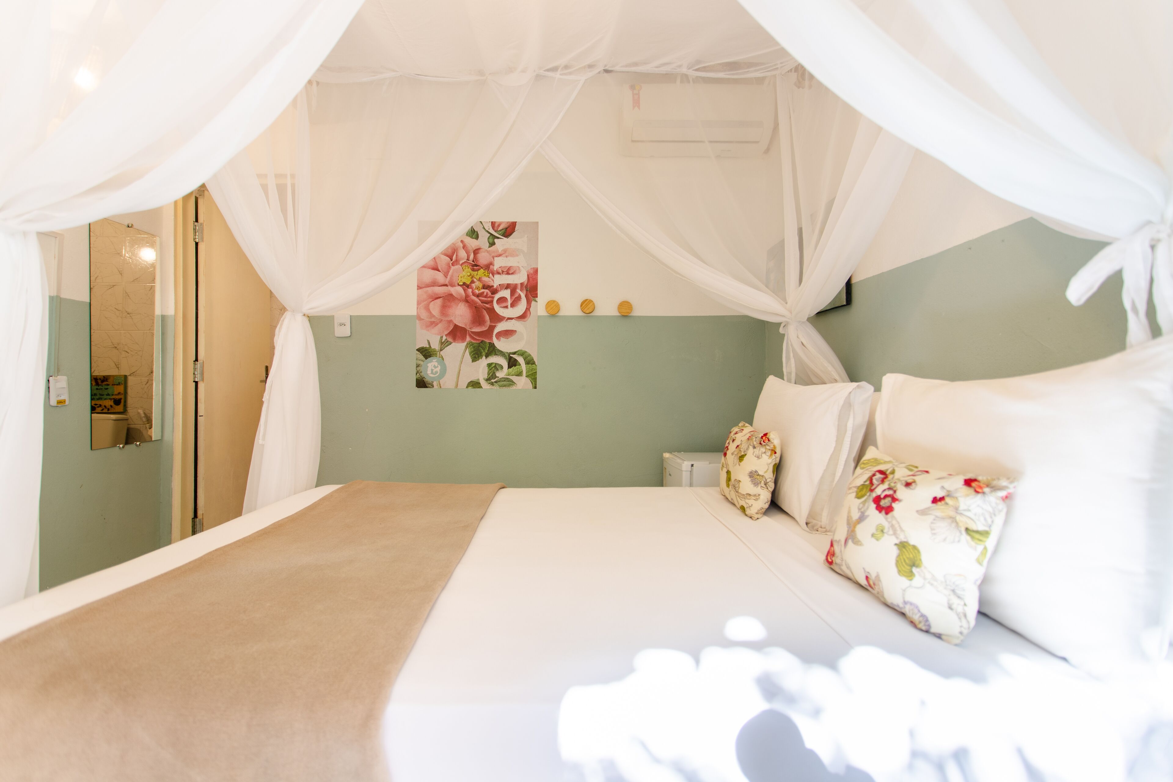 A bedroom with a canopy bed, a floral wall decoration, and a green wall.