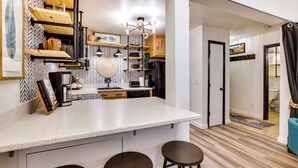 Una cucina moderna con isola centrale, sgabelli da bar e backsplash con motivo a spina di pesce.