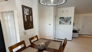 Un'area pranzo con tavolo e sedie in legno, un lampadario e un quadro appeso al muro.