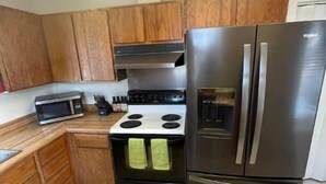 Una cucina compatta con mobili in legno, un frigorifero in acciaio inossidabile, un forno a microonde e un fornello.