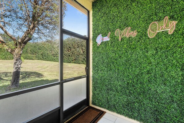 Um quarto com uma janela grande, uma parede verde com um aviso e uma porta.