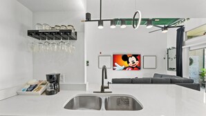 A modern kitchen with a double sink, coffee maker, and wine glasses on the counter. - My Disney Home (Kissimmee)