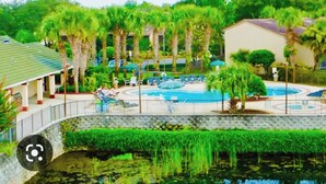 A resort with a swimming pool, palm trees, and a covered seating area. - My Disney Home (Kissimmee)