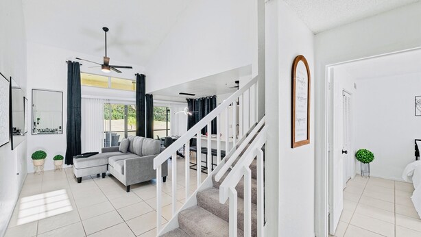 A spacious living area with a staircase, a sofa, and a ceiling fan. - My Disney Home (Kissimmee)