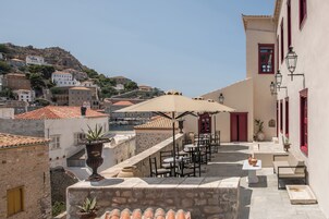 A terrace with outdoor seating, stone walls, and a view of a hillside town.