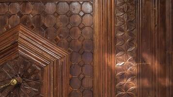 Una puerta de madera con intrincados diseños geométricos y un aldabón de bronce central.