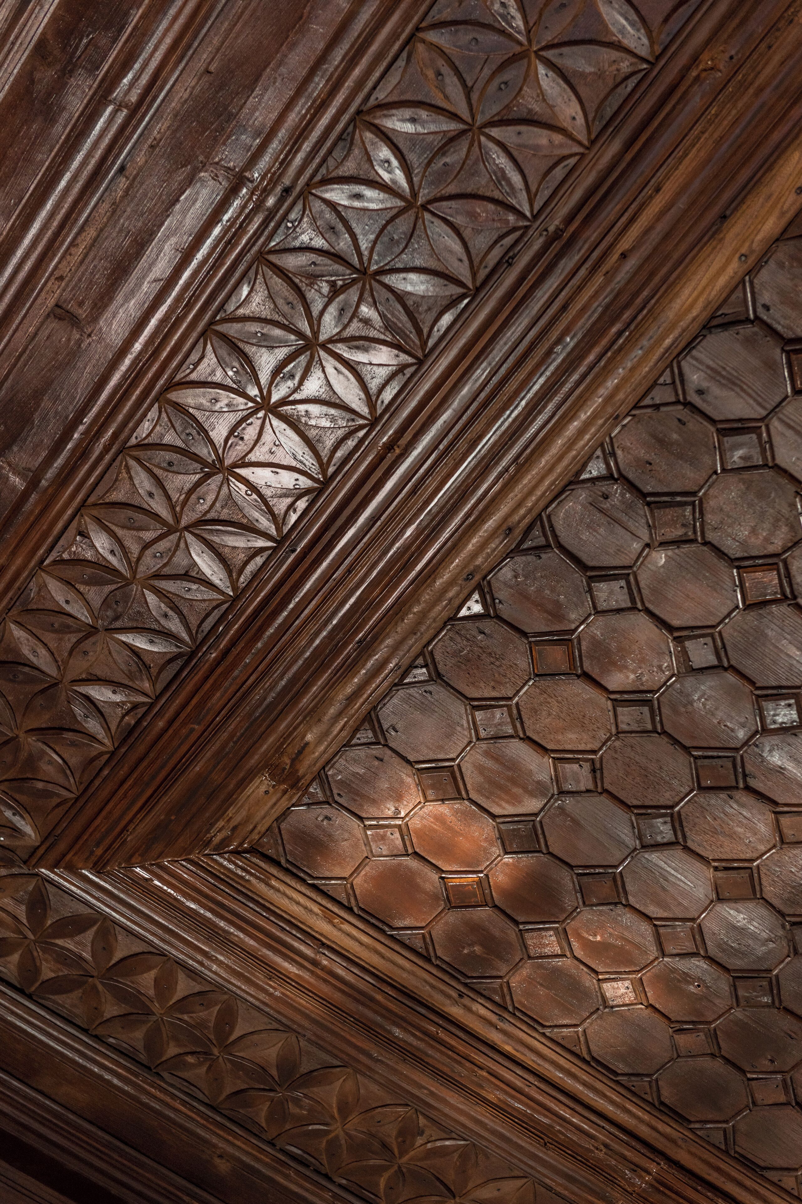 A detailed wooden ceiling with geometric patterns and a honeycomb-like design.