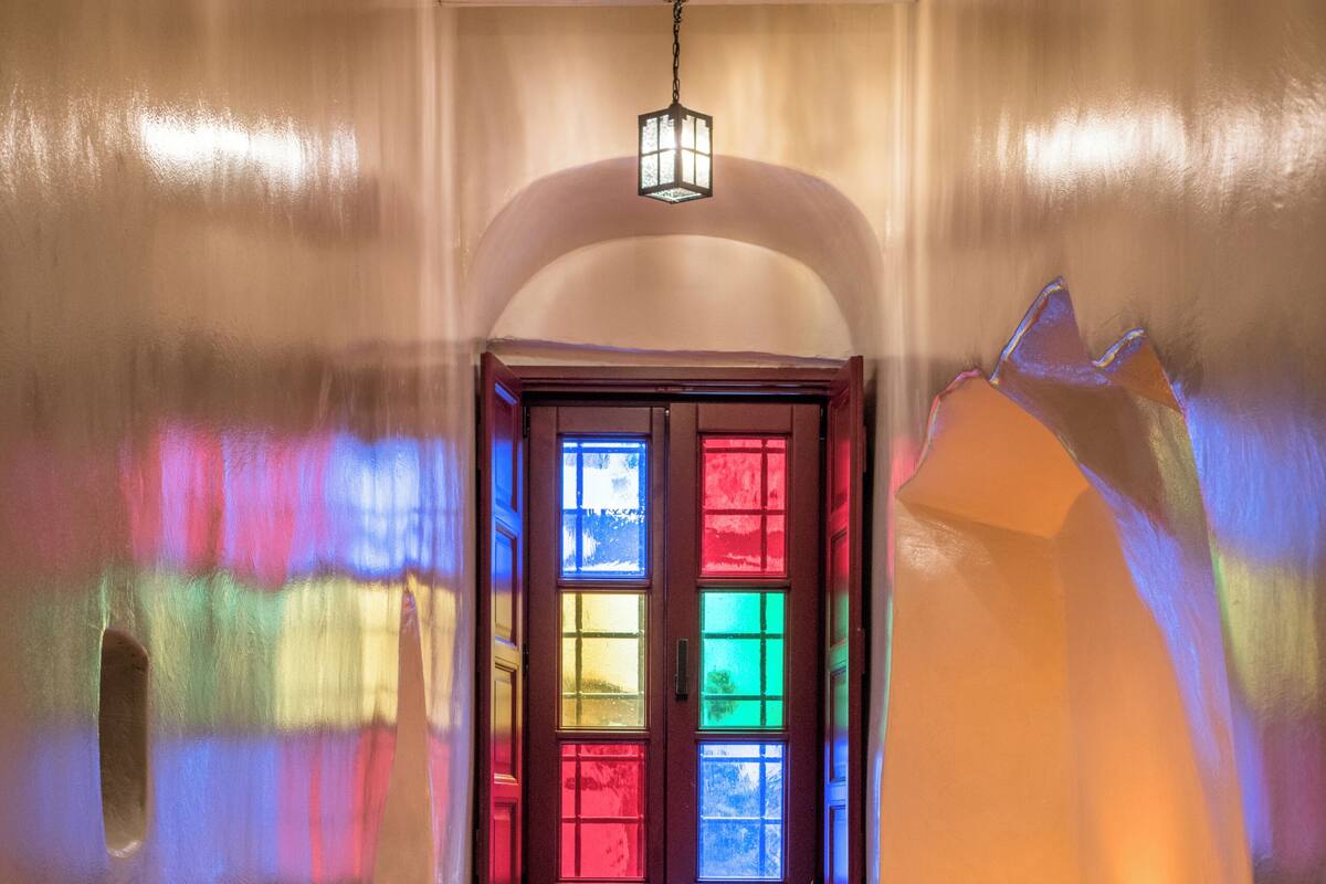 Un baño con bañera, una ventana con vidrieras de colores y una lámpara colgante.