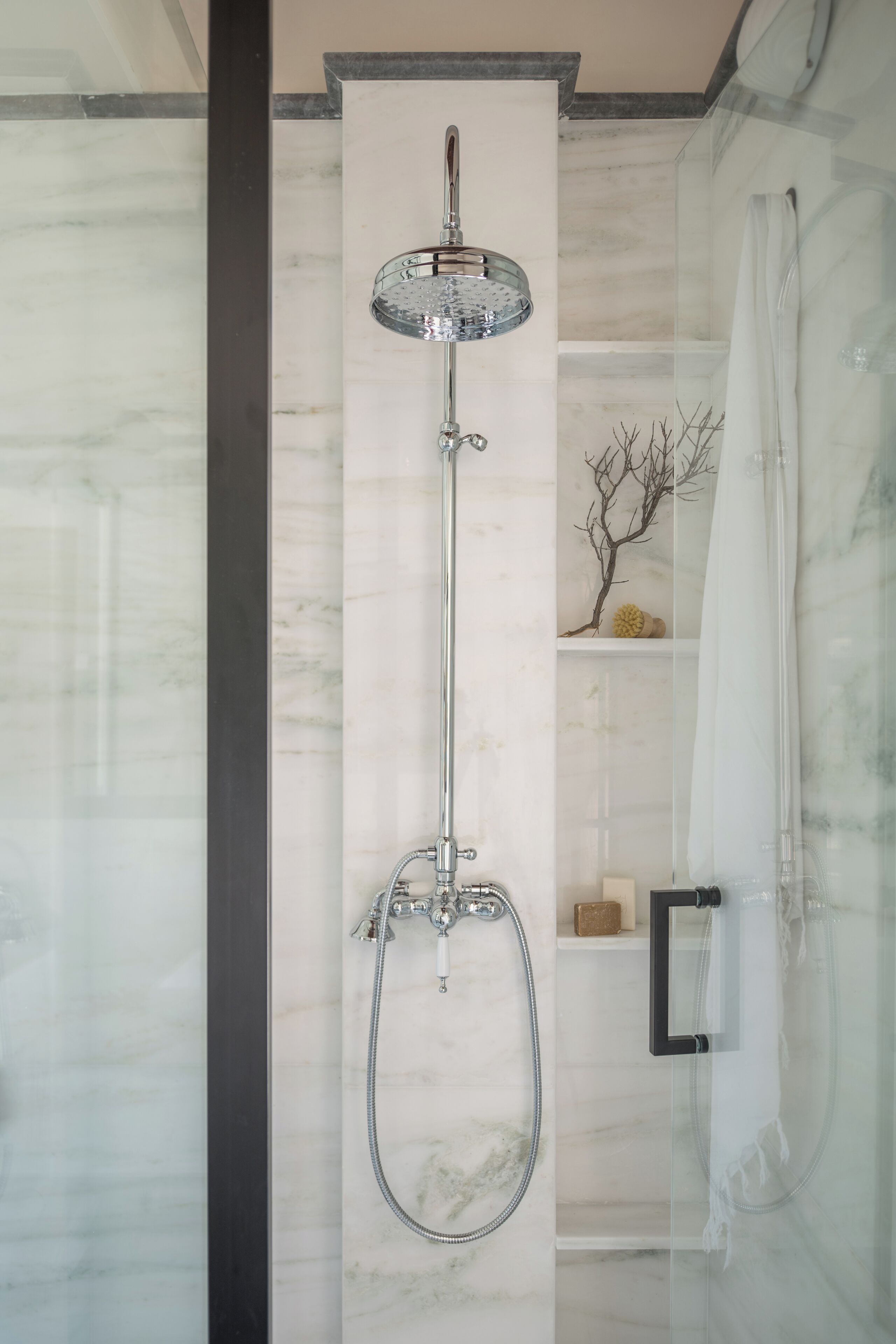 Un baño moderno con ducha de vidrio, paredes de mármol y un diseño minimalista.