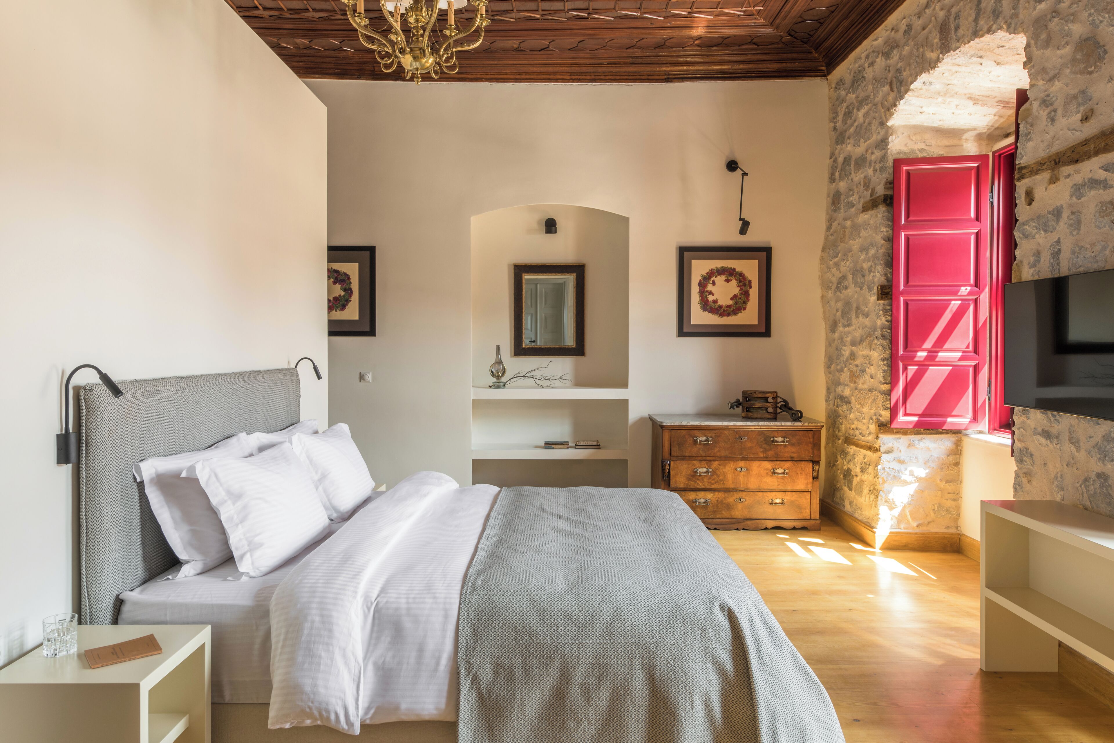 Um quarto com cama, cômoda e televisão.