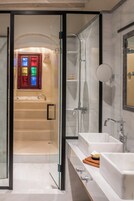 A modern bathroom with a glass-enclosed shower, a large mirror, and a dual sink vanity.