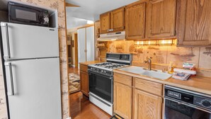 A kitchen with wooden cabinets, a white refrigerator, a stove, and a dishwasher. - Boulder Pines (Big Bear Lake)