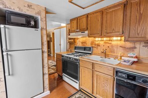 A kitchen with wooden cabinets, a white refrigerator, a stove, and a dishwasher. - Boulder Pines (Big Bear Lake)