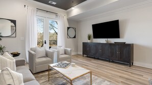 A modern living room with a sofa, armchairs, a coffee table, a TV, and a dark wooden cabinet. - 2 Bedroom, Main Level (Helena)