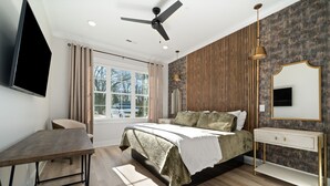 A modern bedroom with a bed, bedside table, TV, and a window. - 2 Bedroom, Main Level (Helena)