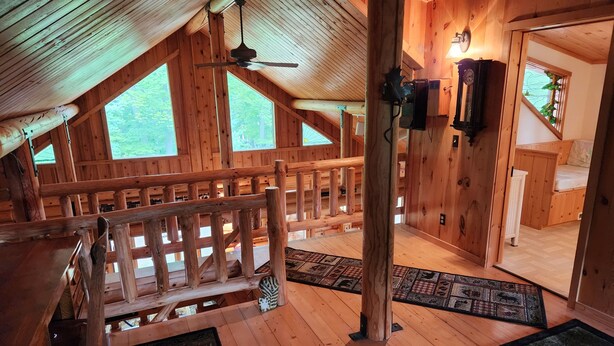 Ein Holzblock-Interieur mit Schlafzimmer auf dem Dachboden, einem Essbereich und einer Treppe.