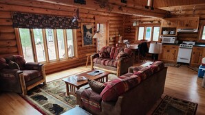 Ein rustikales Holzhaus im Inneren mit Wohnzimmer, Essbereich und Küche.