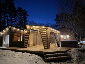 A wooden cabin with a deck, a covered porch, and a hot tub. - Cozy Home Away From Home In Dells with Hot Tub and Firepit (Wisconsin Dells)