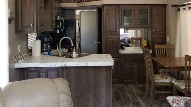 A spacious kitchen with a central island, upper-level seating, and a dining area with wooden furniture. - Cozy tiny home w/lofts deck grill hammock (Phenix City)