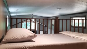 A bedroom with a bed, a ceiling fan, and a staircase leading to an upper level. - Cozy tiny home w/lofts deck grill hammock (Phenix City)