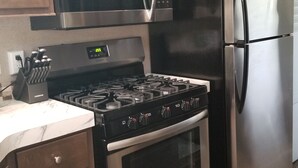 A kitchen with a stainless steel refrigerator, a microwave, a stove, and a built-in oven. - Cozy tiny home w/lofts deck grill hammock (Phenix City)