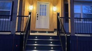 Een houten chalet met een veranda, een voordeur en een trap naar de ingang.