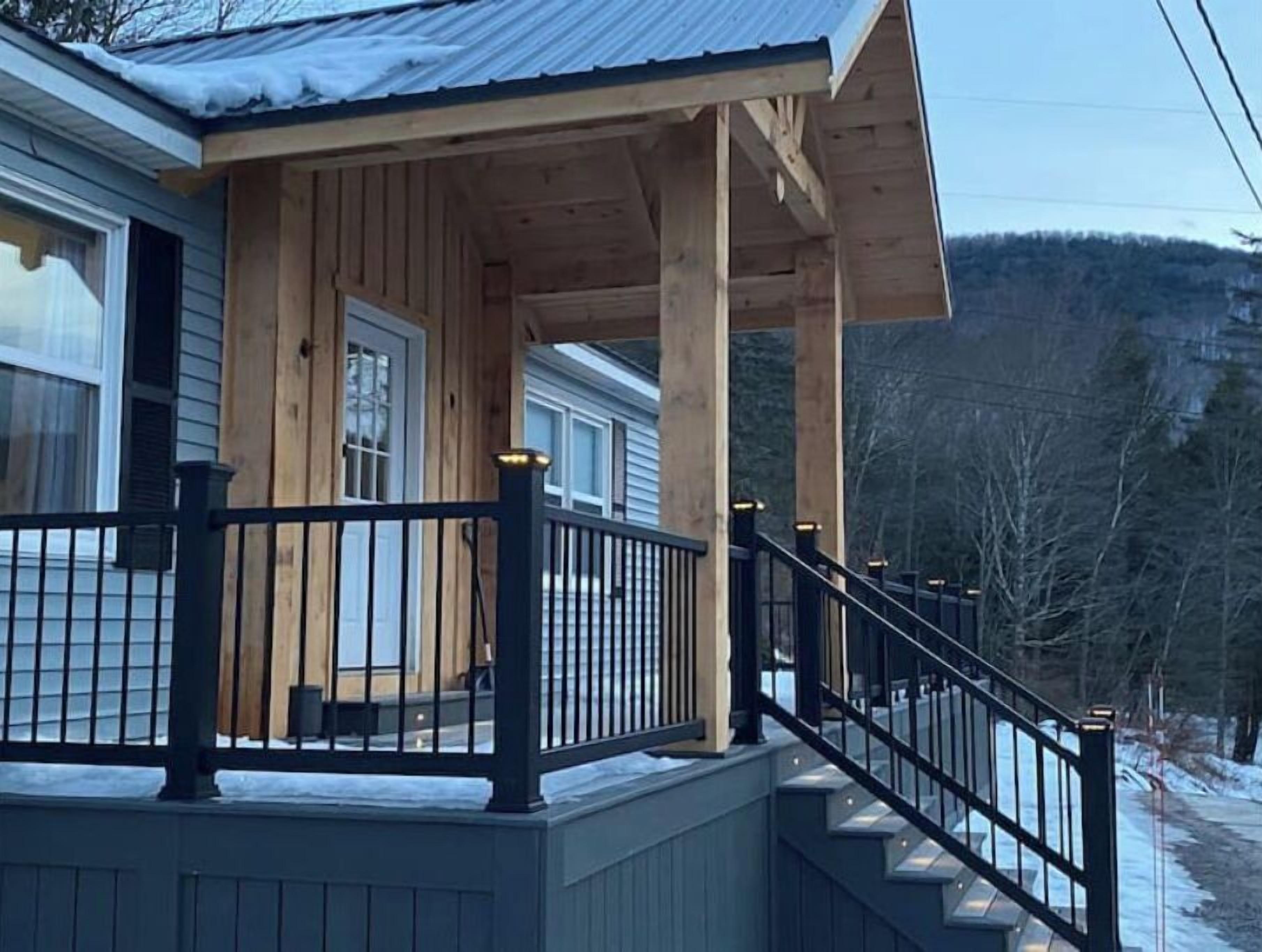 A wooden house with a covered porch and a staircase leading to the entrance.