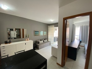A modern living room with a sofa, a dining table, and a kitchen area. - Avenida Oceânica (Salvador)
