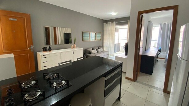 Una cocina moderna con una isla central, armarios blancos y un comedor con mesa y sillas.
