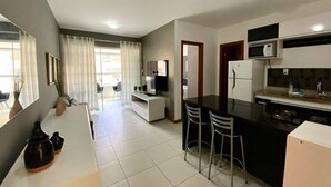 Una cocina moderna con comedor, armarios blancos y un televisor de pantalla plana.