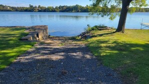 A gravel path leading to a dock by a calm lake, surrounded by grass and trees. - Cottage on Hay Bay. Private boat launch & dock.
 (Greater Napanee)