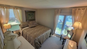 A bedroom with a bed, a chair, a table, and a window with curtains. - Cottage on Hay Bay. Private boat launch & dock.
 (Greater Napanee)