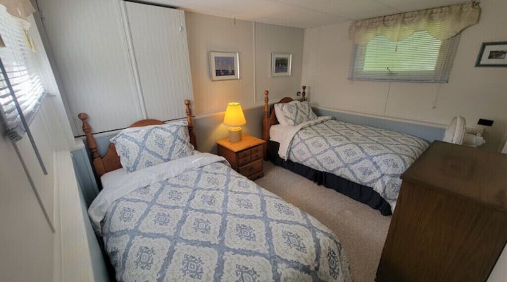 Un dormitorio con dos camas, una mesita de noche con lámpara y un armario.