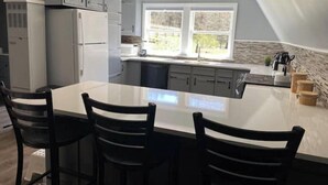 Una cocina moderna con una isla central, armarios grises y un amplio ventanal que proporciona luz natural.
