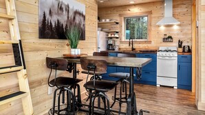 A modern kitchen with wooden walls, a large window, and a stove.