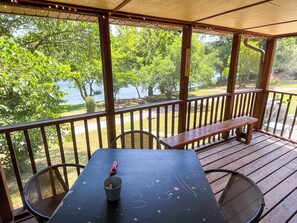 A covered outdoor seating area with a table, chairs, and a bench.