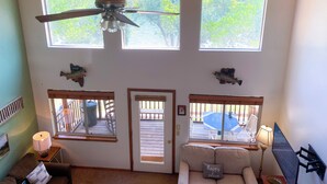 A spacious living room with a ceiling fan, large windows, and a view of the outdoors. - 669 Rainbow Landing Dr (Cotter)