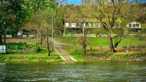 A riverside pathway leading to a house with a deck, surrounded by trees and a grassy area. - 669 Rainbow Landing Dr (Cotter)